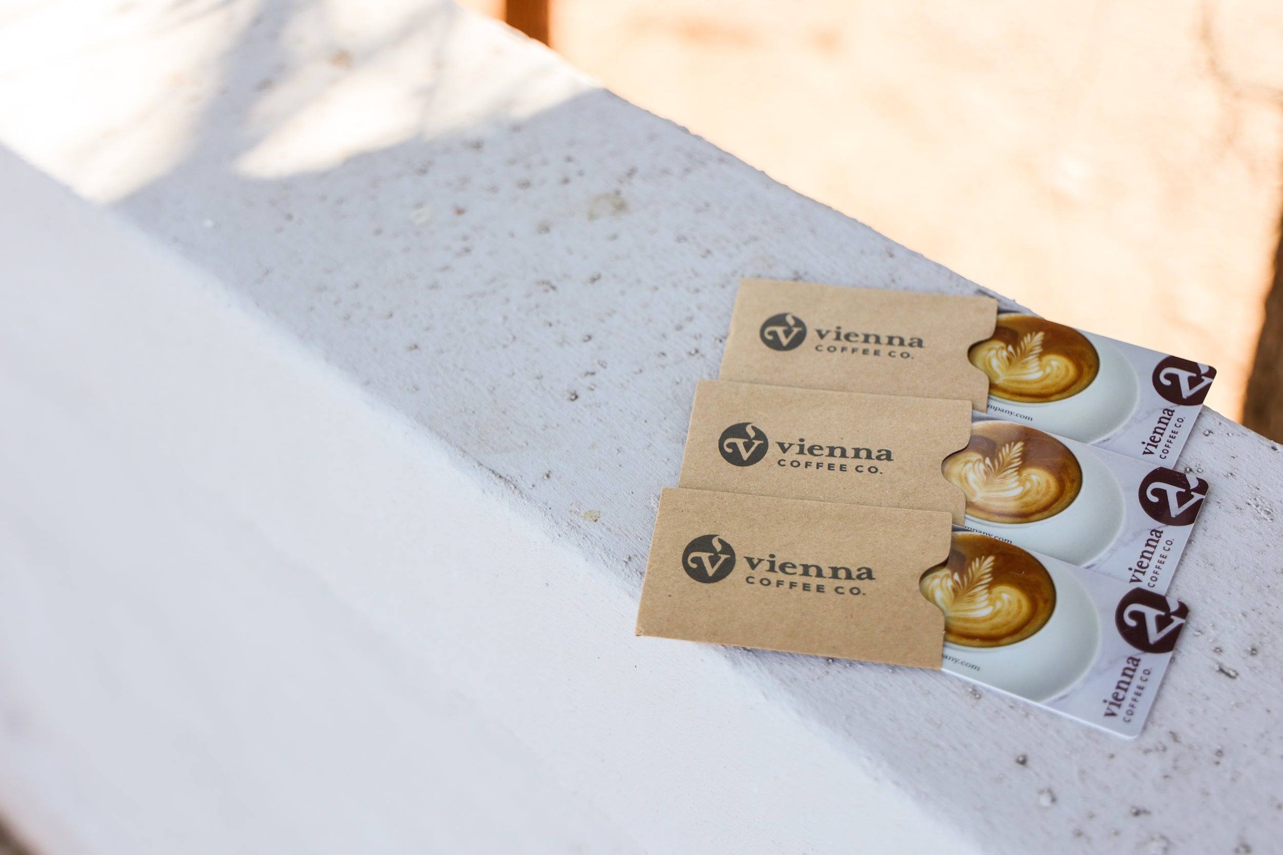 Three Vienna Coffee Co. gift cards on a textured surface with a blurred background
