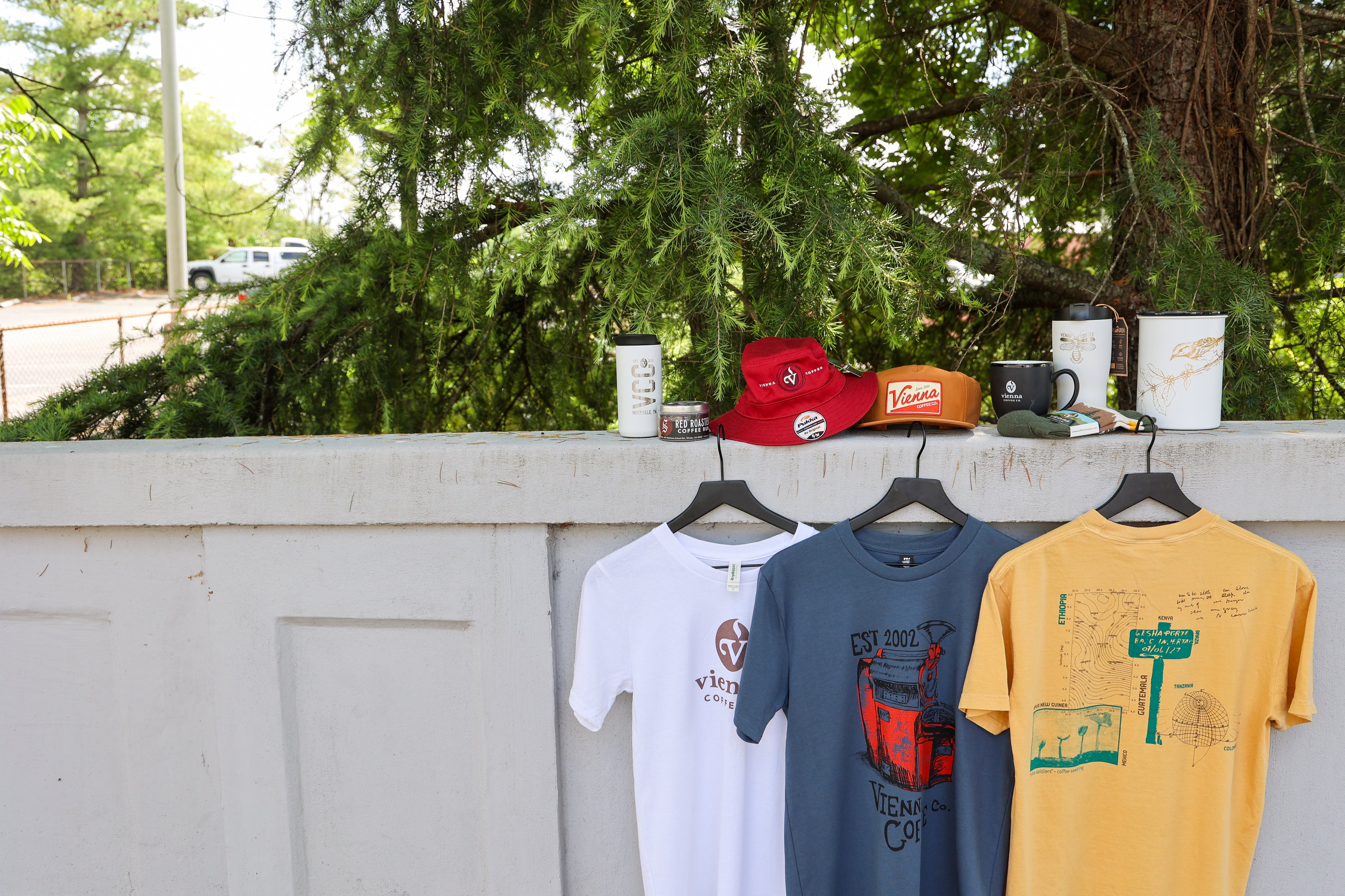 bucket hats, hat, mugs, airscapes, socks, shirts and coffee rubs sitting on a ledge.