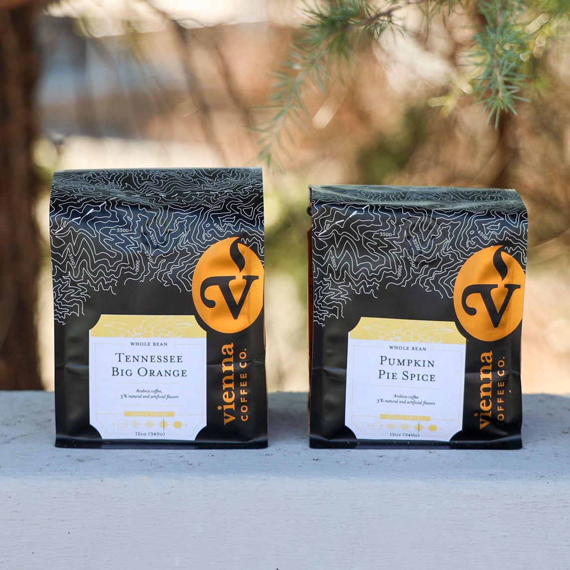 Tennessee Big Orange Flavored Coffee and Pumpkin Pie Spice Flavored Coffee on a cement shelf outside.